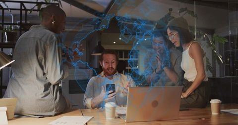 Creative team collaborating around laptop with holographic globe and digital data