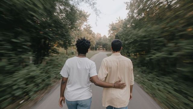 Couple walking arm-in-arm down tree-lined road with motion blur back view romantic