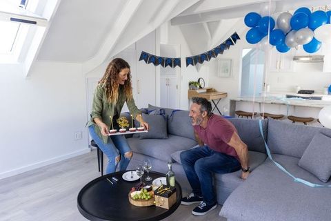 Couple celebrating birthday in bright loft living room with balloons and cupcakes