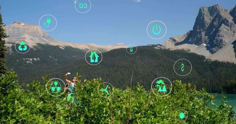 Explorer with smartphone and eco icons in mountainous terrain