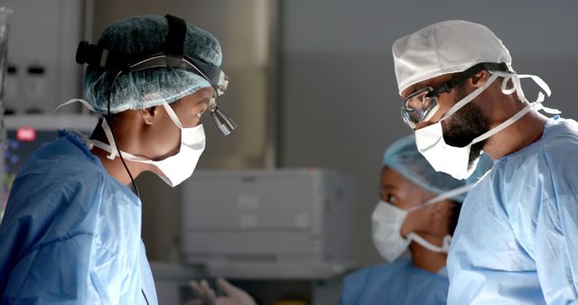 Surgeons in an operating room wearing masks and scrubs while focusing on a procedure. Perfect for depicting scenes in hospitals, healthcare facilities, and medical practices. It is well-suited for articles, magazines, and websites related to surgery, medical education, and healthcare services.