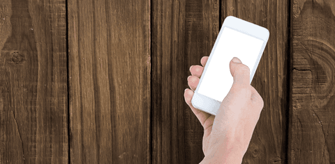 Hand holding smartphone with transparent screen over wooden background