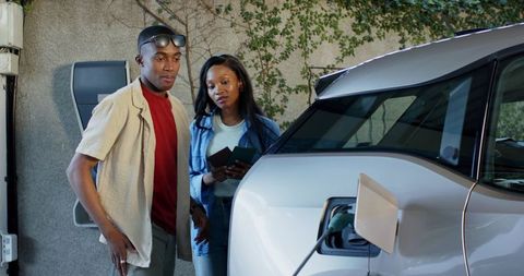 Couple Charging Electric Vehicle at Home with Passports Ready
