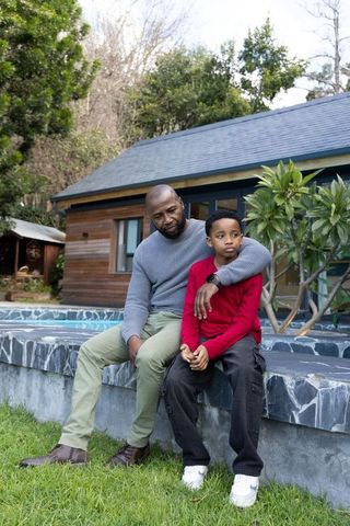 African american father and son sitting on pool edge in backyard bonding moment