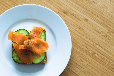 Smoked Salmon Cucumber Toast on White Plate over Bamboo Tabletop