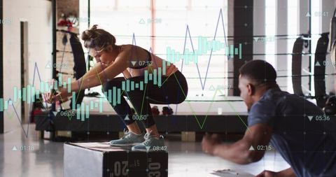 Female Athlete Balancing on Plyo Box While Coach Timing Workout with Performance Graphs
