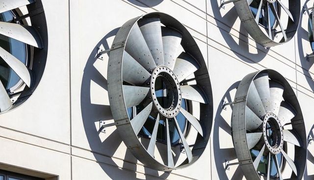 Industrial metal turbine facade casting bold radial shadows on modern building exterior