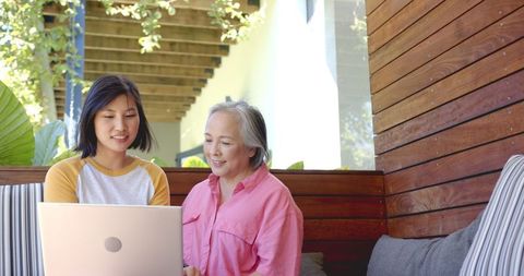 Young Woman Explains Technology to Senior on Cozy Patio