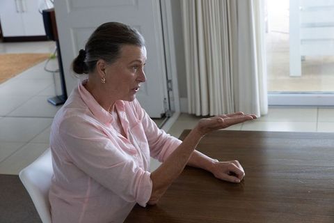 Mature Woman Gesturing During Discussion at Home Dining Table