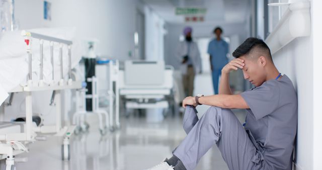 Tired Healthcare Worker Sitting in Hospital Hallway, Feeling Stressed - Download Free Stock Images Pikwizard.com