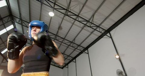 Male boxer wearing blue headgear training in industrial gym low-angle action motion blur