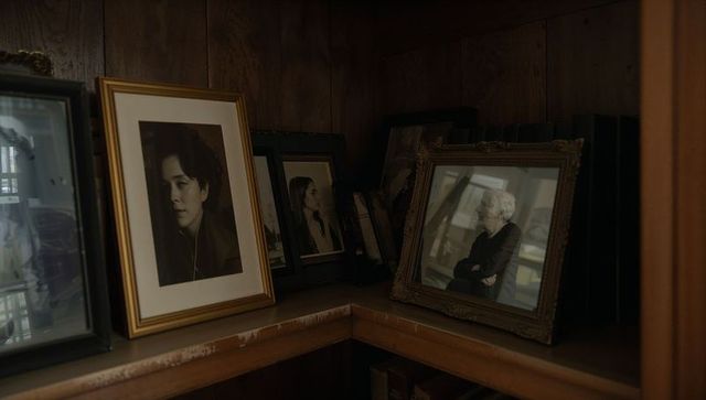 Multigenerational portraits leaning on wooden shelf with vintage frames and warm mood