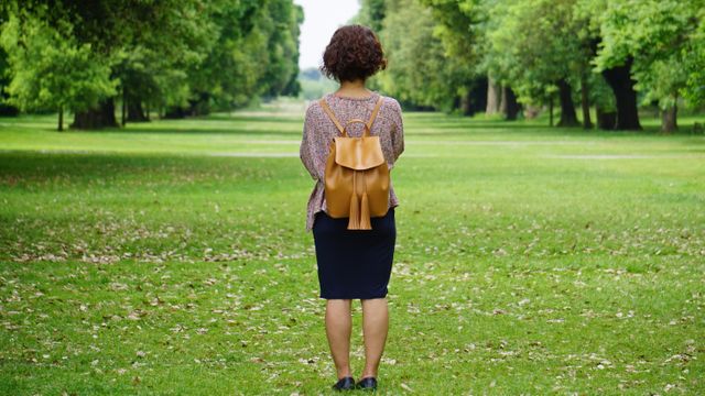 Woman with Backpack Standing Alone in Peaceful Park - Download Free Stock Photos Pikwizard.com