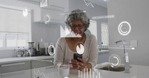 Senior woman using smartphone at sunlit minimalist kitchen island with augmented data overlays