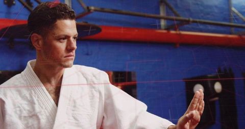 Focused martial artist blocking with open palm in dojo training for discipline, defense