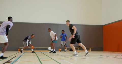 Indoor basketball team practicing fast-paced dribbling and tight defense on hardwood court