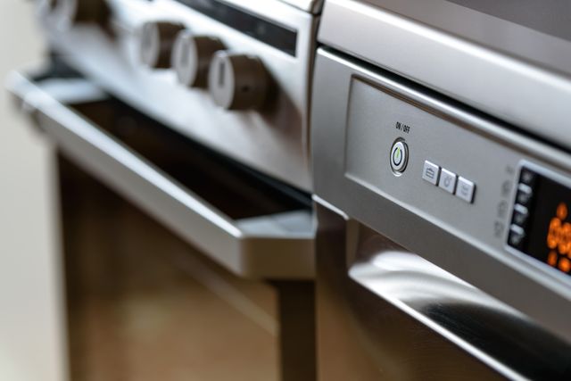 Stainless steel appliances add a modern touch to any kitchen. This image includes a close-up view of the control panels on high-end kitchen appliances, such as a stove, oven, and possibly a dishwasher. Perfect for use in articles or advertisements related to kitchen design, home renovation, modern technology in the kitchen, or appliance reviews.