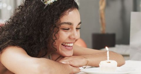 Joyful Young Woman Celebrating Birthday with Candle on Cupcake