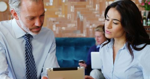 Business Professionals Using Tablet in Cafe Meeting