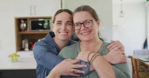 Smiling Lesbian Couple Embracing in Modern Kitchen