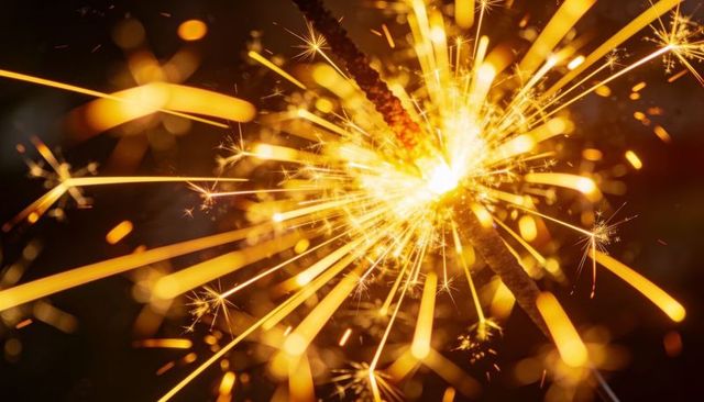 Golden sparkler closeup with radiant sparks and warm bokeh glow for festive celebration