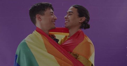 Happy lgbtq couple wrapped in rainbow flag celebrating joy