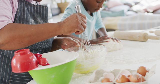Happy african american grandmother baking with granddaughter kneading dough, in kitchen, copy space. Family, health, togetherness and domestic life.