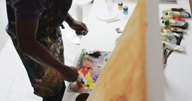 Midsection of african american male painter mixing paints in artist studio. art, creative and leisure time concept.