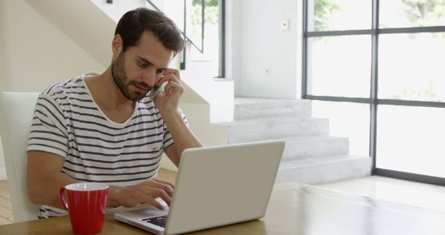 Young Man Working Remotely on Laptop While Talking on Phone - Download Free Stock Images Pikwizard.com