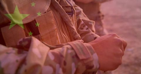 Adjusting Tactical Vest Wrist Straps with Chinese Flag Overlay at Desert Sunrise