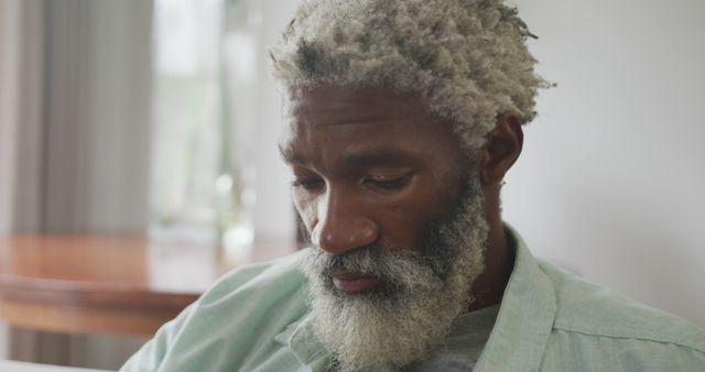 Pensive elderly African American man with a beard contemplating. Ideal for themes around wisdom, experience, introspection, aging, calmness, and thoughtfulness. This can be used in articles or advertisements focusing on senior care, mental health, or personal growth.