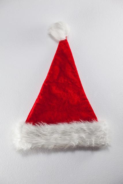 This close-up of a festive red Santa hat on a white background captures the essence of Christmas spirit. Ideal for holiday greeting cards, promotional materials, festive decorations, and seasonal advertising.