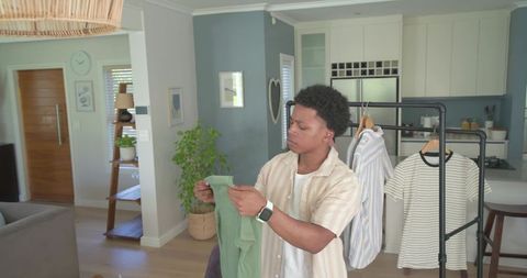 African american man inspecting casual wardrobe in modern open-plan home choosing outfit