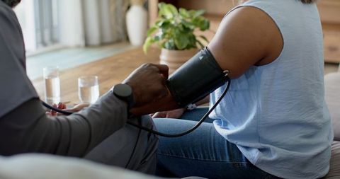 African american caregiver measuring blood pressure of woman during home health visit