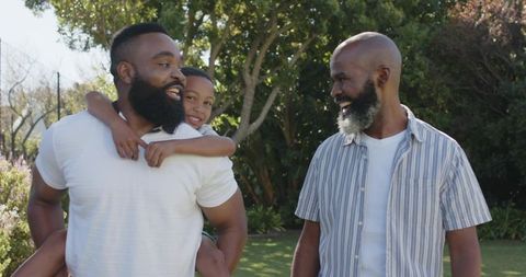 Father, grandfather, and young son enjoying sunny day in backyard garden