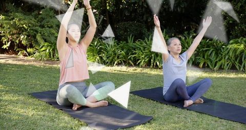 Intergenerational women practicing outdoor yoga stretching on lawn for wellness and balance