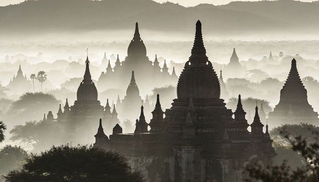 Misty bagan temple silhouettes at dawn, layered pagodas and ancient stupa skyline in sepia
