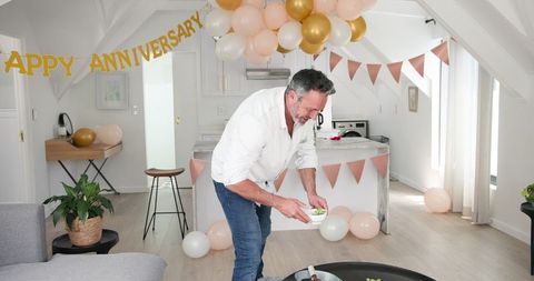 Man preparing anniversary celebration at home with decorations