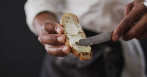 Chef Spreading Butter on Bread Slice with Knife