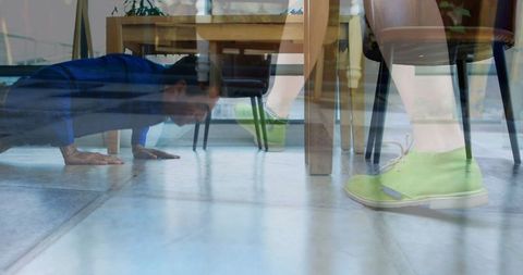 Man Performing Push-Up Under Table with Green Shoes for Home Fitness
