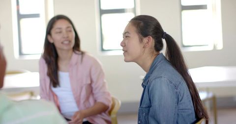 Teenage Asian student listening in collaborative classroom discussion wearing denim jacket