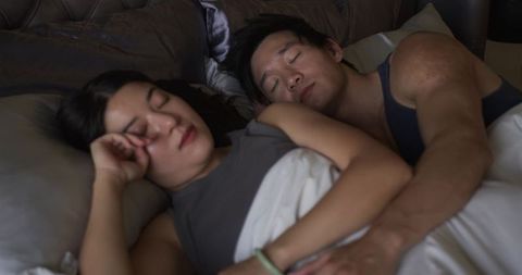 Couple sleeping embracing in dim bedroom soft morning light and intimate cuddle