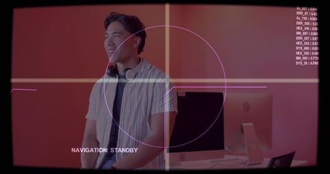 Smiling creative professional standing by desktop in pink-lit studio wearing headset and striped tee