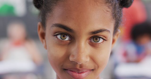 This vibrant image captures the close-up portrait of a smiling African American girl with striking green eyes. It evokes a sense of confidence and joy. Ideal for use in educational content, diversity promotion campaigns, family-oriented publications, or materials highlighting children's health and wellbeing.