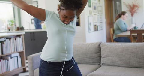 Joyful Teenage Girl Dancing with Earphones in Living Room
