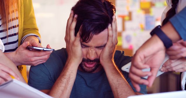 Overwhelmed Man Surrounded by Colleagues in Busy Office - Download Free Stock Images Pikwizard.com