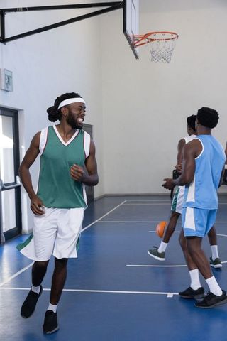Athletic Young Men Jogging on Indoor Basketball Court