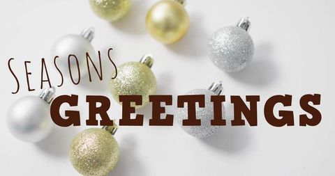 Seasons greetings over gold and silver glitter christmas baubles on white background