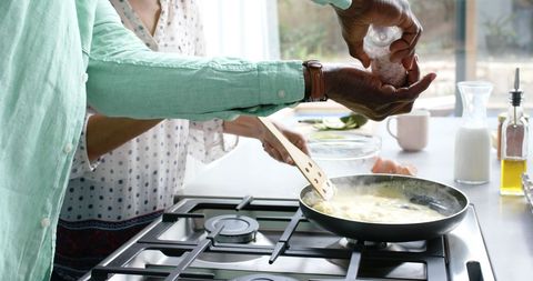Couple cooking together at home spicing dishes
