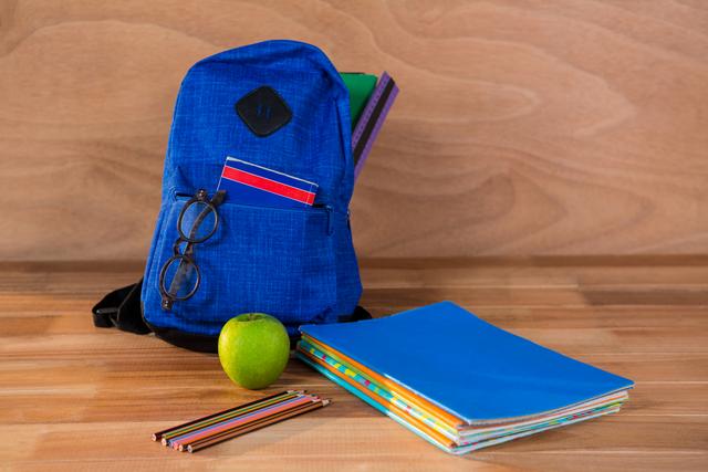 School bag with books and stationery on a wooden table. Ideal for back-to-school promotions, educational materials, and study-related content.